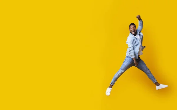 Portrait of jumping black guy on yellow studio background — Stock Photo, Image