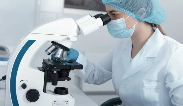 Mulher trabalhando com microscópio moderno em laboratório médico leve — Fotografia de Stock