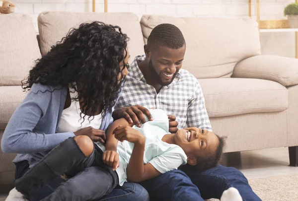 Kochający afro rodzice łaskoczą swoją córeczkę, bawią się w domu — Zdjęcie stockowe