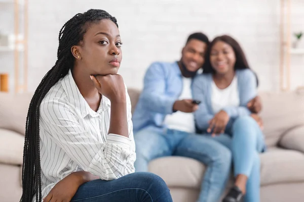 Neid Mädchen sitzt allein, während ihre Dating-Freunde sich auf der Couch umarmen — Stockfoto
