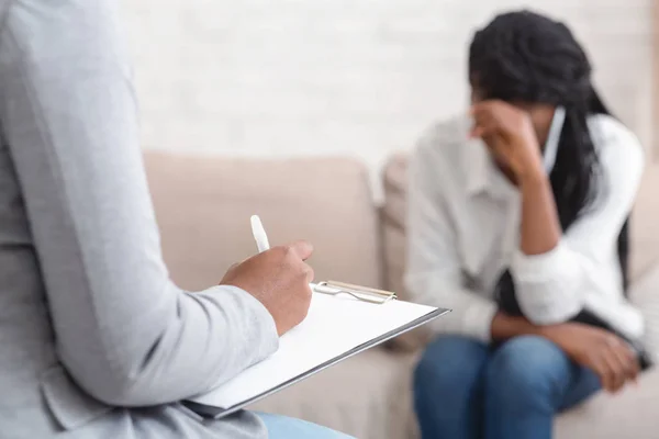 Onherkenbare vrouwelijke psycholoog noteert problemen van vrouwelijke patiënt tijdens therapiesessie — Stockfoto