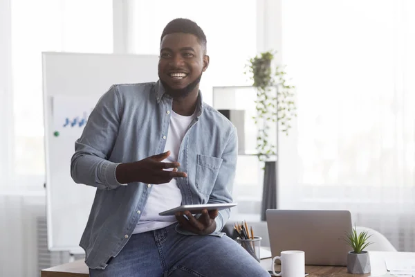 Glimlachende zwarte manager met digitale tablet, iets uitleggen aan zijn collega 's — Stockfoto