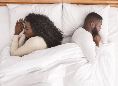 Genç Afro çift rahat bir yatakta sırt sırta kestiriyorlar.