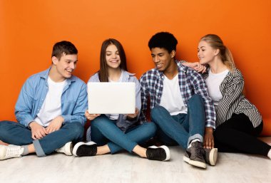 Çeşitli öğrenciler dizüstü bilgisayara bakıyor, internette videolar izliyorlar.