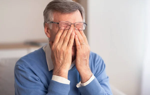 Homem Sênior Massageando Olhos Cansados Sentado No Sofá Em Casa — Fotografia de Stock