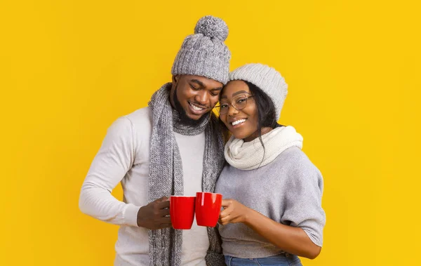 Invierno alegre chico y chica bebiendo café sobre amarillo fondo —  Fotos de Stock
