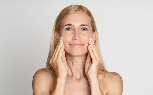 Vrouwen van middelbare leeftijd verwijderen make-up met wattenschijfjes — Stockfoto