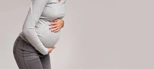 Menina grávida que sofre de dor abdominal sobre fundo cinza, cortado — Fotografia de Stock