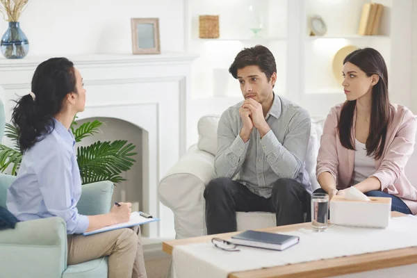 Junger emotionaler Mann erzählt Spezialist von Problemen, Frau beobachtet ihn — Stockfoto