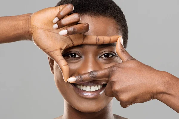 Beautiful african woman holding frame from fingers near her eyes — Stock Photo, Image