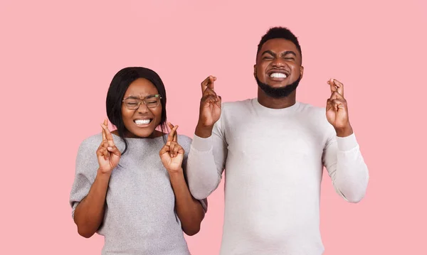 Pareja negra cerrando sus ojos cruzando dedos con esperanza — Foto de Stock