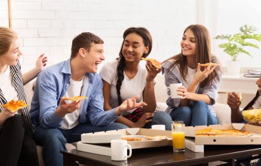 Mutlu genç oda arkadaşları evde pizza yiyip sohbet ediyorlar.