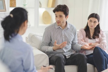 Young man explaining himself to family therapist clipart