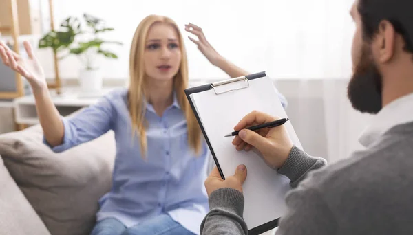 Donna emotiva che parla con psicoterapeuta, medico che prende appunti — Foto Stock