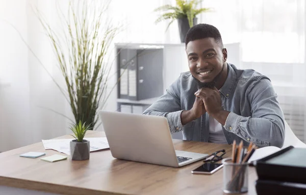 Портрет улыбающегося чернокожего сотрудника на рабочем месте в офисе — стоковое фото