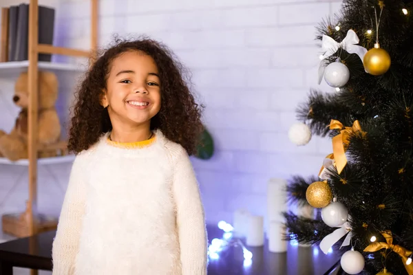 Linda menina afro-americana posando perto de árvore de Natal decorada — Fotografia de Stock