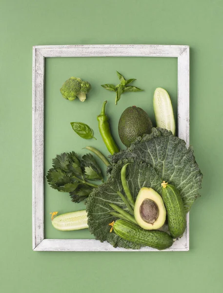 Green composition of fresh organic vegetables inside wooden frame — Stock Photo, Image