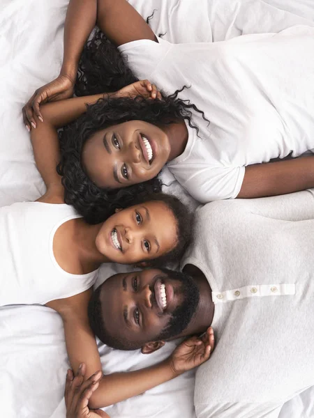 Vista superior da família afro alegre relaxando na cama juntos — Fotografia de Stock