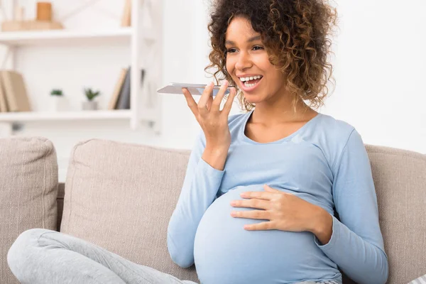Счастливая беременная женщина отправляет голосовое сообщение по телефону — стоковое фото