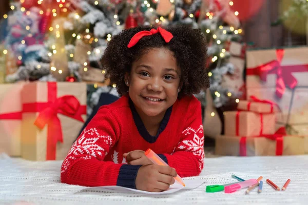 Очаровательная черная девочка пишет список подарков — стоковое фото