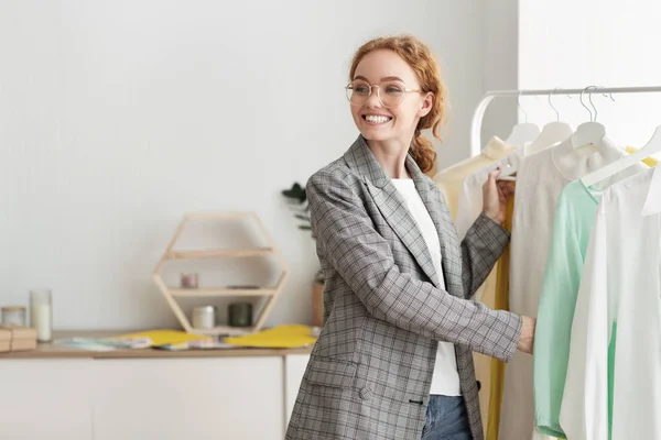 Mujer feliz eligiendo ropa en la sala de exposición de diseñadores — Foto de Stock