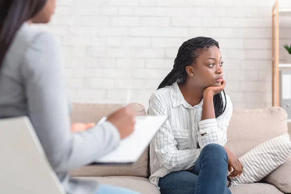 沉思的非洲裔美国女人坐在心理治疗师办公室的沙发上 — 图库照片