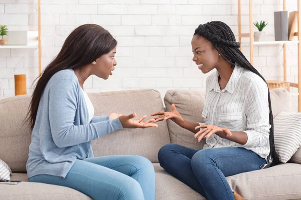 Two girlfriends sitting on sofa and arguing with each other — Stock Photo, Image
