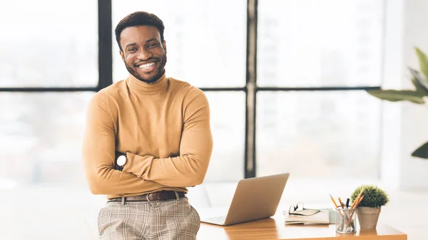 Afrikaanse zakenman zittend op bureau kijkend naar camera — Stockfoto