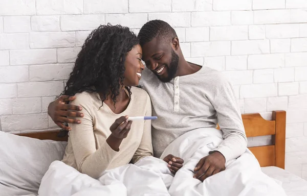 幸せなアフリカのカップル持って正妊娠テストしながらベッドに座って — ストック写真