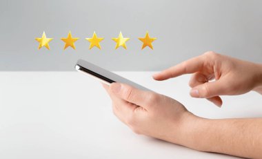 Kadın eli cep telefonu kullanıyor ve beş yıldızlı not veriyor.