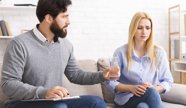 Psychologist offering glass of water to crying depressed woman — Stock Photo, Image