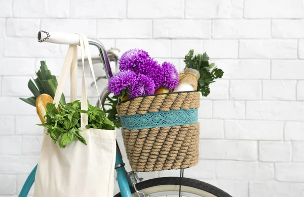 Bicicleta con productos frescos y hermosas flores sobre la pared de ladrillos blancos —  Fotos de Stock