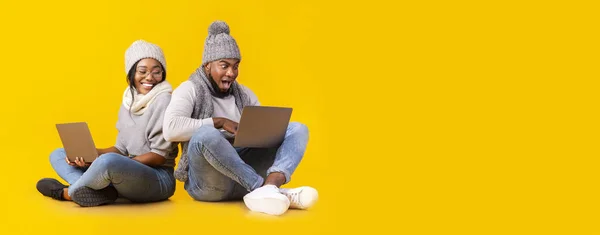 Casal de inverno preto sentado no chão com laptops — Fotografia de Stock