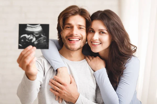 Glückliches Millennial-Paar mit Ultraschalluntersuchung seines werdenden Babys — Stockfoto