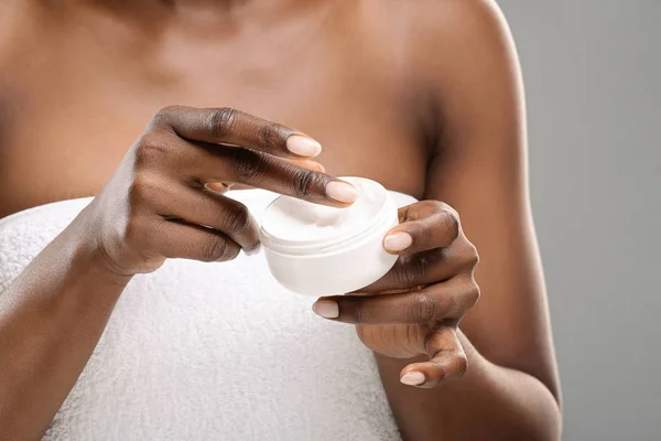 Onherkenbare zwarte vrouw die een pot hydraterende crème vasthoudt — Stockfoto