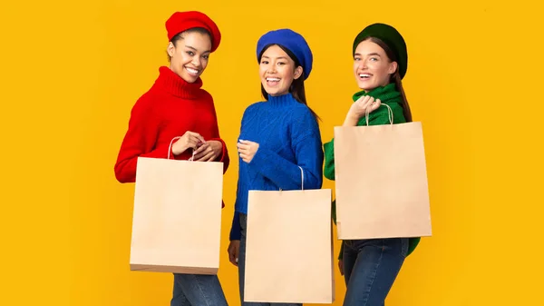Trois filles heureuses tenant des sacs à provisions vierges sur fond jaune — Photo