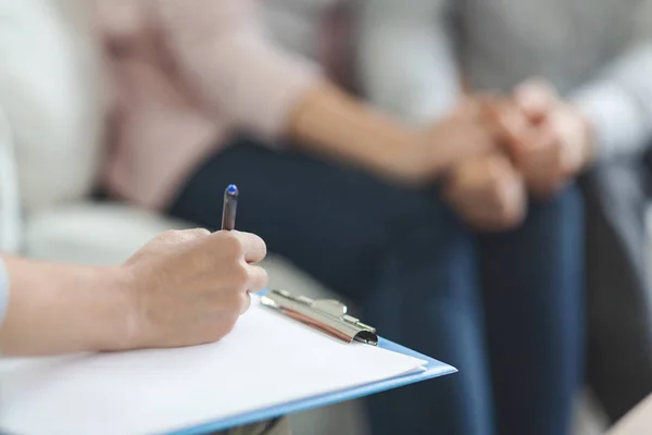 Terapeut skriva i tom anteckningsblock vid familjerådgivning session — Stockfoto