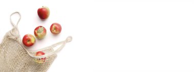 Beyaz arkaplanda kırmızı elmalar yeniden kullanılabilir ağ torbasında