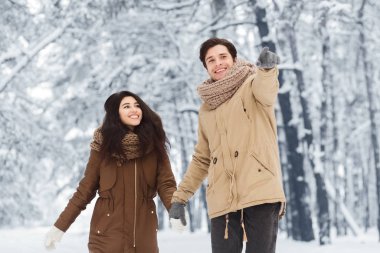 Mutlu adam kız arkadaşıyla yürüyor. Kış Ormanı 'nda bir şeyler gösteriyor.