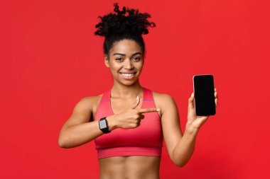 Sportif siyah kadın akıllı telefon boş ekranını işaret ediyor