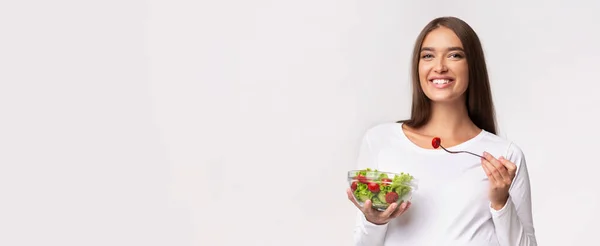 Werdende Dame isst Gemüsesalat im Stehen vor weißem Hintergrund, Panorama — Stockfoto