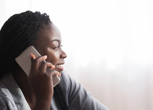Профиль портрет улыбающейся африканской женщины, разговаривающей по мобильному телефону — стоковое фото