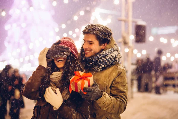 Petit ami fermeture copines yeux donnant cadeau de Noël debout dans la ville — Photo