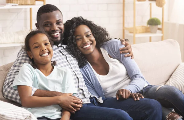 Amoroso afro família abraçando e sorrindo para a câmera em casa — Fotografia de Stock