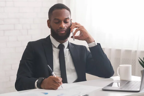 Negro hombre de negocios hablando por teléfono móvil mientras trabaja en la oficina — Foto de Stock