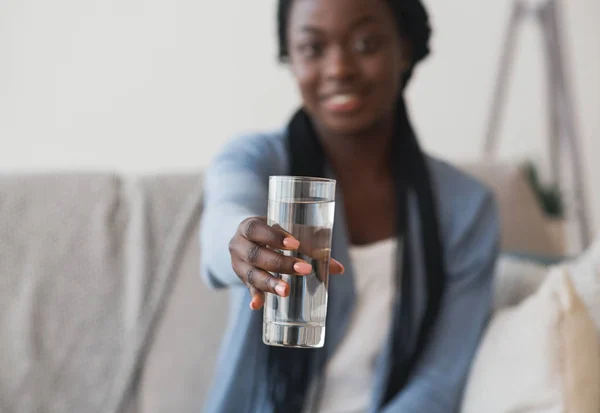 Ragazza nera che tiene il vetro di acqua minerale offrendolo sulla macchina fotografica — Foto Stock