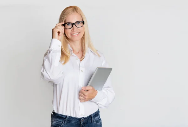 Geschäftsfrau mittleren Alters mit digitalem Tablet vor grauem Hintergrund — Stockfoto