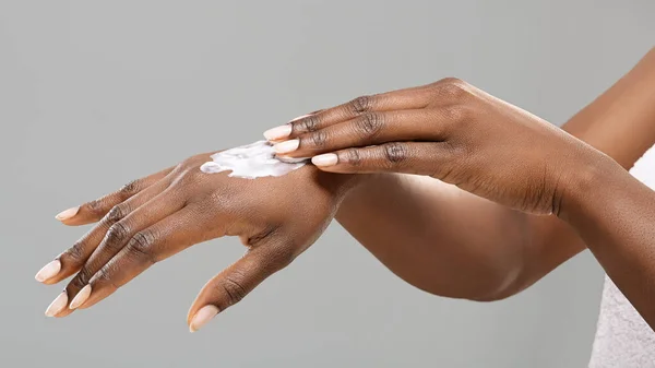 Ręce nierozpoznawalnej czarnej kobiety z zastosowanym balsamem do ciała. — Zdjęcie stockowe