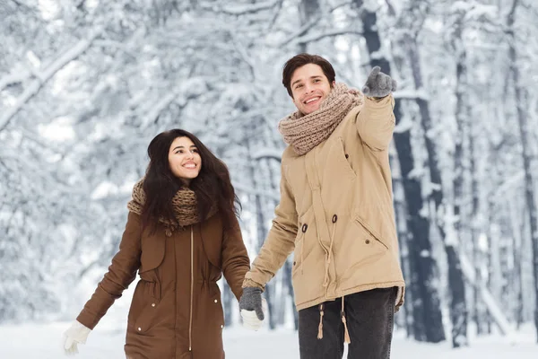 Feliz hombre caminando con novia mostrando algo en invierno bosque —  Fotos de Stock
