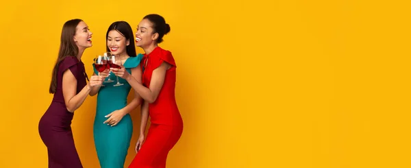 Trois filles tenant des verres à vin rouge parlant sur fond jaune — Photo
